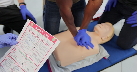 CPR First Aid training concept. Back view of woman holding first aid instruction during cpr training class