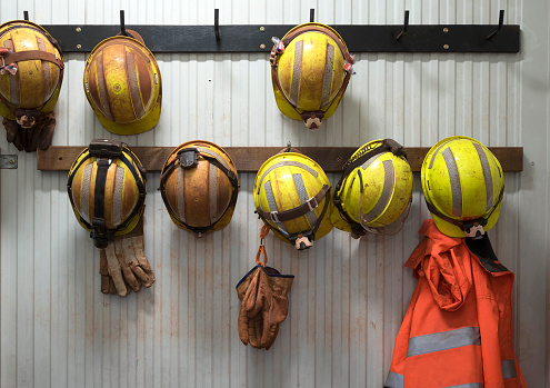 Safety helmets and gloves hang from a rack on a mining site