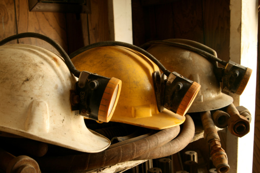 Three mine helmets on a shelf. Main focus on center helmet.